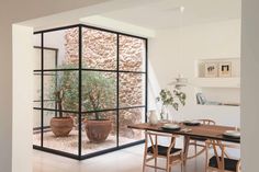 a dining room with a table and chairs in front of a glass wall that looks out onto the outdoors