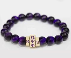 Omega Psi Phi Fraternity Beaded Bracelet Elevate your style with this exquisite deep purple beaded bracelet, perfect for adding a touch of elegance to any outfit. Each bead is carefully selected for its rich color and lustrous finish, reminiscent of fine amethysts. The centerpiece of this stunning accessory is an elegant gold-tone bar that proudly displays the Greek letters “ΩΨΦ” alongside “1911,” commemorating the fraternity’s historic founding year. Whether you’re dressing up for a special occ Purple Beaded Bracelets With Round Beads For Gifts, Purple Beaded Bracelets With Round Beads As Gift, Purple Round Beaded Bracelet For Gift, Purple Beaded Bracelets As Gift, Purple Stretch Bracelet With Round Beads As Gift, Purple Beaded Bracelet With Spacer Beads As Gift, Purple Beaded Bracelets With Spacer Beads As Gift, Purple Bracelets With 8mm Beads As Gift, Amethyst Beaded Bracelets With Spacer Beads As Gift