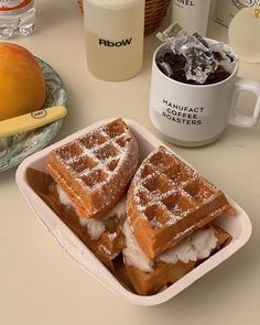 two waffles sitting on top of a white plate next to a cup of coffee