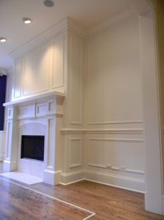 an empty living room with white walls and wood flooring on the other side of the fireplace