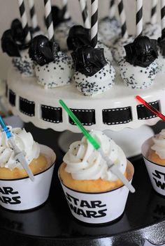 star wars themed cupcakes on a black and white cake plate with candles in them