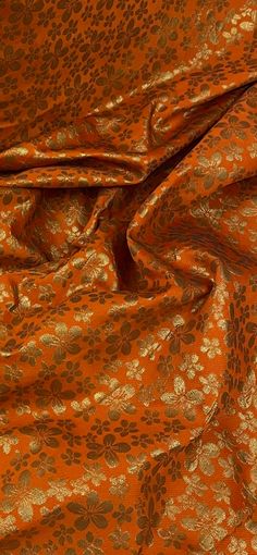 an orange and gold fabric with flowers on it