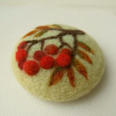 a close up of a brooch with berries on it's back and leaves painted on the front