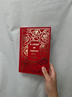 a hand holding up a red book with roses on it