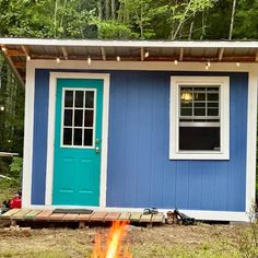 a small blue and white cabin with a fire pit