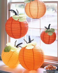 some paper pumpkins hanging from a window sill