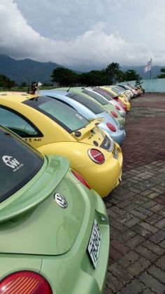 a row of cars parked next to each other on top of a brick road with mountains in the background