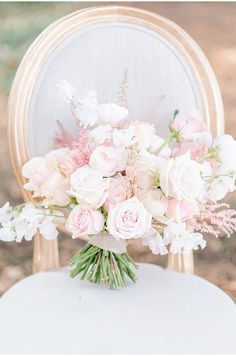 a bouquet of pink and white flowers sitting on top of a chair with an oval back