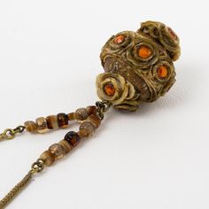 This is part of Chairish’s Costume Jewelry assortment.  French jewelry artist Henry Perichon (aka Henry) designed this elegant brass and Talosel resin necklace in the 1960s. The long necklace features   a brown-beige Talosel resin ball pendant topped with topaz orange crystal faceted rhinestones. The necklace is finished with a gilded brass serpentine chain ornate with natural quartz beads and a hook-closing clasp. This piece is unsigned, but the beige-brown Talosel pendant and the specific orna Topaz Orange, Resin Ball, Jewelry Artist, French Jewelry, Orange Crystals, Quartz Beads, Ball Pendant, Resin Necklace, Accessories Jewelry Necklace