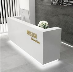 a white marble reception desk with flowers on it and the word design written in gold