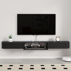 a flat screen tv mounted to the side of a wall next to a white rug