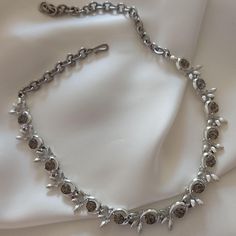 The choker is in shiny silver metal. It has a pattern of small leaves enclosing medium-sized, smoke-colored round faceted crystals. The choker is made up of a single thread and 14 crystals. The closure is with an adjustable hook (which has been replaced). The choker is signed BSK, the brand is on the necklace. You can find the whole set, choker and earrings in the "parure" section. This choker is really beautiful, very elegant and refined. Perfect to wear on special occasions, when you want to h Vintage Silver Beaded Choker, Formal Silver Choker With Sparkling Stones, Silver Choker With Sparkling Stones For Formal Occasions, Silver Rhinestone Choker For Evening, Silver Metal Choker For Evening, Vintage Metal Rhinestone Necklace With Sparkling Stones, Vintage Silver Jeweled Necklace, Vintage Jeweled Silver Necklace, Vintage Silver Rhinestone Necklace For Evening