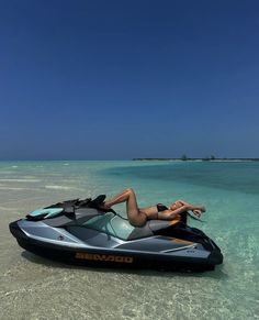 a woman laying on top of a jet ski in the ocean next to an island