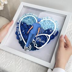 a person holding a blue heart shaped cake in a box with the words i love you, nurse on it