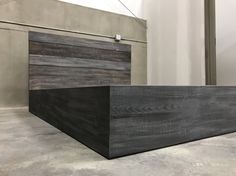 a large wooden box sitting on top of a cement floor next to a building wall