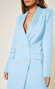 a woman wearing a light blue suit with gold buttons on the lapel and sleeves