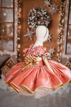 a mannequin wearing a pink and gold dress in front of a christmas display