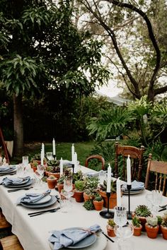 an outdoor table set with plates and place settings