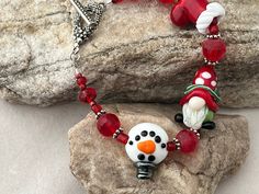 Christmas Gnome Lampwork Bead Bracelet.  Bracelet features a Gnome made in my home studio.  I strung the bracelet with three strands of seed beads to increase the holiday feel.  Lampwork beads are flameworked in my home studio and kiln annealed for strength and quality Festive Adjustable Hand-strung Beaded Bracelets, Red Christmas Holiday Bracelet, Festive Faceted Multi-strand Beads, Festive Multi-strand Faceted Beads, Handmade Multi-strand Red Beads, Beads Christmas, Red Bracelet, Green Bracelet, Christmas Bracelet