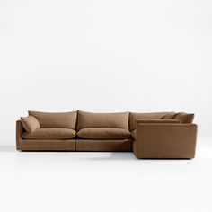 a large sectional couch with pillows on the top and bottom, sitting in front of a white wall