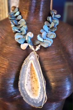 "A single strand of blue-gray polished jasper teardrop gemstone beads supports a gorgeous, heavily crystallized druzy geode wire-wrapped gemstone statement pendant.  Two silver tone metal bicone beads flank the pendant which measures approximately 4.75\" x 2.25\".  This adjusts from 18-22\" with a silver tone hook clasp and 4\" extender chain.  The back is finished with ornate silver tone filigree beads, aurora borealis rhinestone rondelles and small faceted crystals.  Given the neutrality of th Teardrop Agate Jewelry For Healing, Healing Teardrop Agate Jewelry, Teardrop Agate Wire Wrapped Jewelry, Wire Wrapped Teardrop Agate Jewelry, Bohemian Chalcedony Wire Wrapped Jewelry, Bohemian Wire Wrapped Chalcedony Jewelry, Turquoise Agate Jewelry With Large Stone, Bohemian Teardrop Agate Jewelry, Blue Agate Geodes With Natural Stones