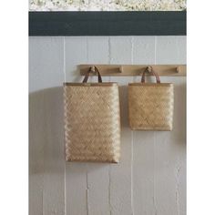 two woven bags hanging from hooks on a wall