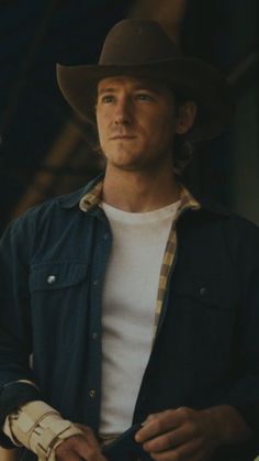 a man wearing a cowboy hat and holding a baseball glove in his right hand while looking at the camera