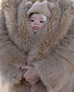 a woman holding a baby wrapped in a fur coat