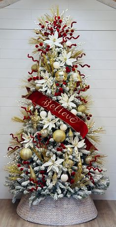 a decorated christmas tree with red ribbon and gold ornaments