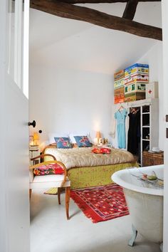 a room with a bed, bathtub and rugs