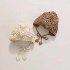 two crocheted hats sitting next to each other on top of a white surface