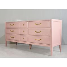 a pink dresser with gold handles and drawers