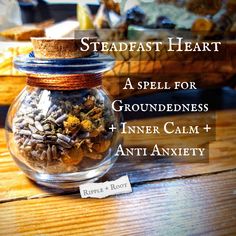 a glass jar filled with dried herbs on top of a wooden table next to a sign that says steadfast heart