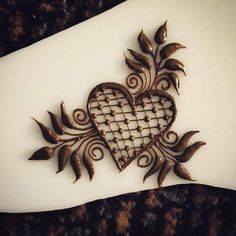 an intricately designed heart on top of a white plate with brown leaves and vines