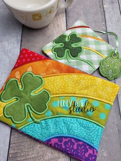 three pot holders with shamrocks on them sitting next to a coffee cup and spoon