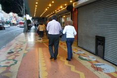 two people walking down the sidewalk in front of a building