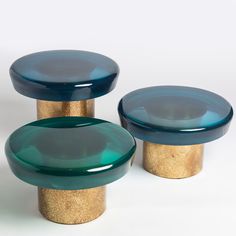 two blue glass stools sitting next to each other on top of a white surface