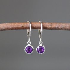 "Sweet faceted bright Purple Amethyst round stones are bezel set in small silver charms.  These dangle from silver lever back huggie hoops.  These classic earrings are perfect for any age and any occasion!  Please note these charms are small.  These earrings are also available in a smaller size... www.etsy.com/listing/710543884/amethyst-earrings Amethyst bezels: 6mm Silver charms: 6x9mm Silver huggie hoop: 1x12mm Total length of earrings: 7/8\" Length is approximate.  All silver is sterling. As Purple Gemstone Hoop Earrings, Sterling Silver Dangle Earrings With Bezel Setting, Elegant Amethyst Dangle Hoop Earrings, Purple Dangle Birthstone Earrings, Purple Dangle Earrings With Birthstone, Sterling Silver Earrings With Bezel Setting As Gift, Round Amethyst Gemstone Earrings, Sterling Silver Jewelry With Bezel Setting And Dangle Shape, Everyday Round Earrings With Bezel Setting