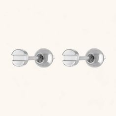 two pairs of stainless steel studs on a white background, with one ear hole in the middle