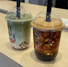 two plastic cups filled with food sitting on top of a wooden table next to each other