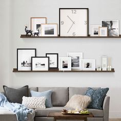 a living room filled with furniture and framed pictures on the wall above a gray couch