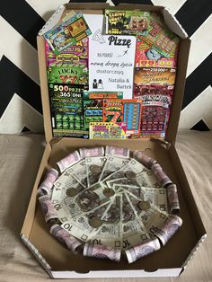 an open box containing a pizza with lots of money in it's bottom half