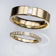 two gold wedding bands with diamonds on each one and a baguette diamond in the middle