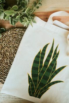 a white bag sitting on top of a wooden table next to a basket and plant