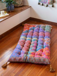 a multicolored floor cushion with tassels on the top and bottom part