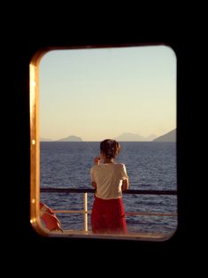 a woman standing on a boat looking out at the ocean