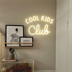 a neon sign that says cool kids club on the side of a wall above a shelf