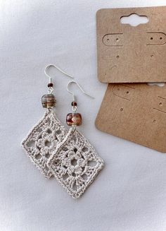 a pair of earrings sitting on top of a piece of paper next to a card