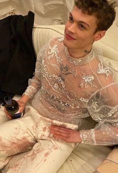 a woman sitting on top of a couch covered in white paint and holding a remote control