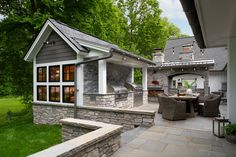 an outdoor kitchen and dining area in a home's backyard with stone steps leading up to it